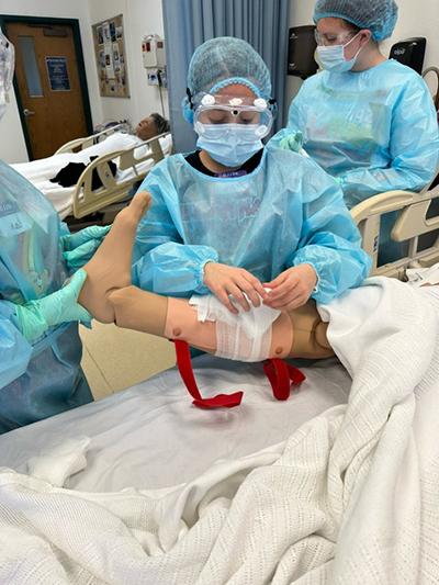 护理探索项目成员包扎受伤的人工合成病人的小腿.